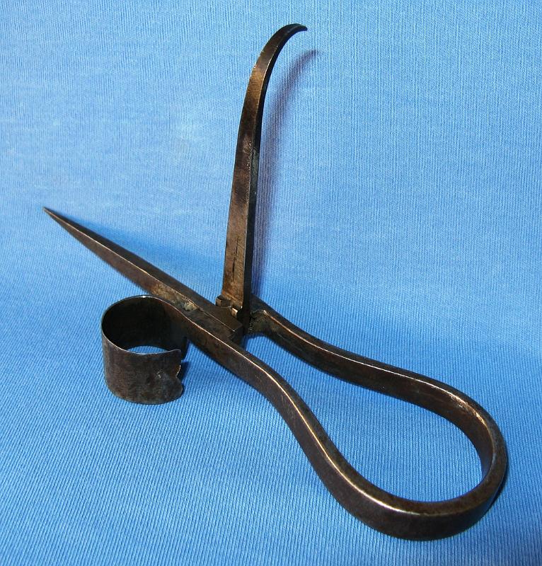 Pocket Folder Open I.jpg - POCKET FOLDING CANDLESTICK - Unique hand forged steel pocket folder, shaft and hook both fold and rotate independently snapping firmly into place each quarter turn, very small folder with full size thimble, 3 5/8 in. closed and 5 1/2 in. open, unmarked  (This folding candlestick is one of the smallest folders I've ever seen and is even more interesting in that it's equipped with a full size thimble to hold a miner's candle.  The maker's workmanship is exquisite and the folding mechanism looks like it was made by a machinist, a testament to the blacksmith's skill.  The stick was purchased by a collector at a flea market in Denver, Colorado in 1968.  The stick is unmarked but since the stick was found in Denver, it is thought the folder is of Colorado origin.  My special thanks to Leo Stambaugh whose keen eye notes that this folder is very similar to the design of the Larsen patent folding candlestick shown as No. 238 in Wilson and Bobrink's Miners' Candlesticks Guide.  The Neils Larsen folding hook and spike model was awarded patent No. 151,297 on May 26, 1874 while Larsen was living in Mill City, Colorado Territory.  Larsen soon after moved to the Leadville area.  The Larsen stick in addition to the folding spike and hook includes a fold out knife blade for cutting fuse.  While somewhat smaller (the Larsen stick is 3 in. closed and 4 1/4 in. open), Larsen's patent and this pocket folder are a very similar design and share many of the same features including the folding mechanism, open thimble, hook shape and construction.  The only known example of the Larsen patent is the patent model itself currently on display at the Henry Ford Museum in Dearborn, MI.  The 1874 patent model is the earliest known example of a miner's candlestick with hook.  It is quite interesting that this folding stick and the Larsen's patent stick without the folding blade look too much alike to be coincidental.  Speculation that this could be a pre-patent model of Larsen's design or a copy of Larsen's design by a competent blacksmith makes the search for its history even more interesting.  Research continues.)